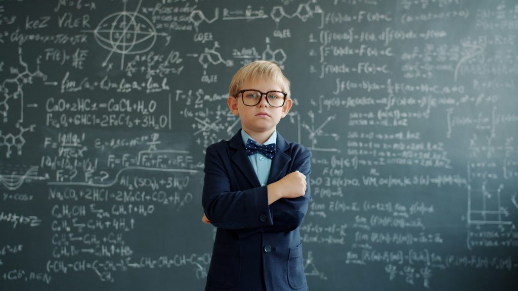 Bright young boy in front of a blackboard filled with formulae, representing intelligence, education and AI-assisted learning.